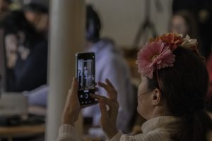 Pasākuma apmeklētāja ar telefonu fotografē Gunta Tālera uzstāšanos